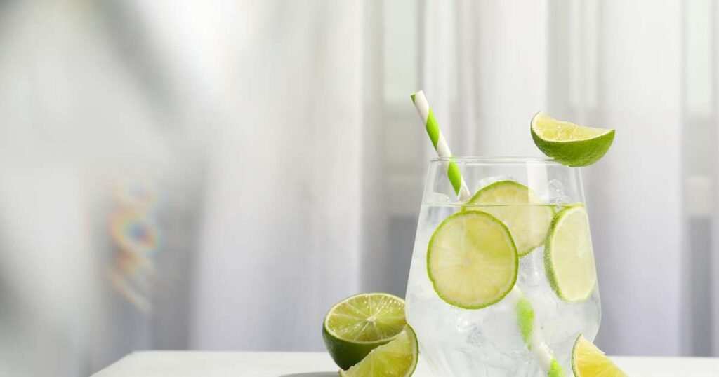 Copo de água com limão fresco e fatias de limão ao lado, simbolizando saúde e bem-estar