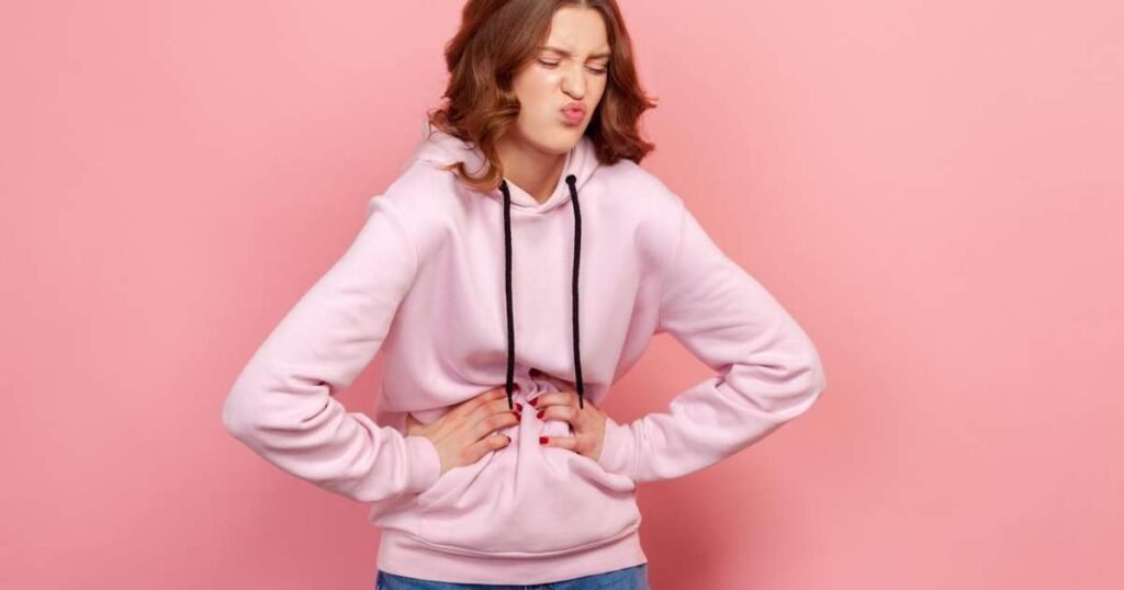 Mulher olhando preocupada enquanto segura a barriga, representando a relação entre fome e irritação.