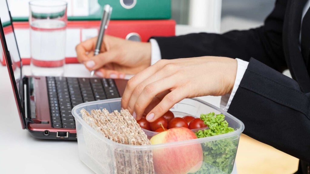 Mulher bebendo água e preparando refeição saudável para emagrecer