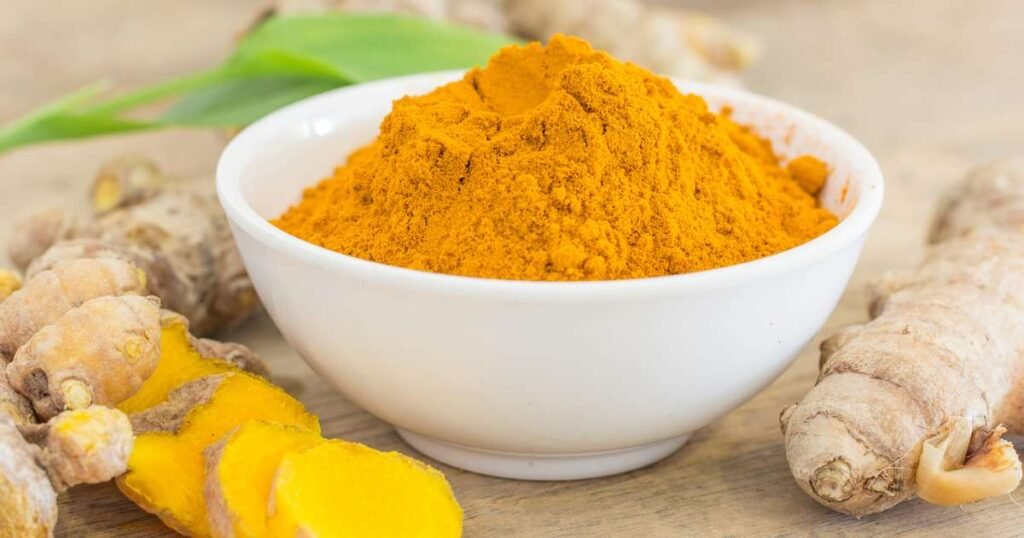 Cúrcuma em pó e raiz fresca sobre uma tábua de madeira