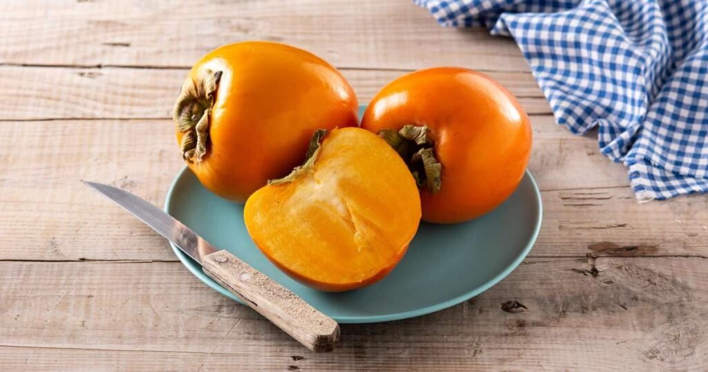 Fruta caqui fresca com casca, destacando sua cor vibrante e textura